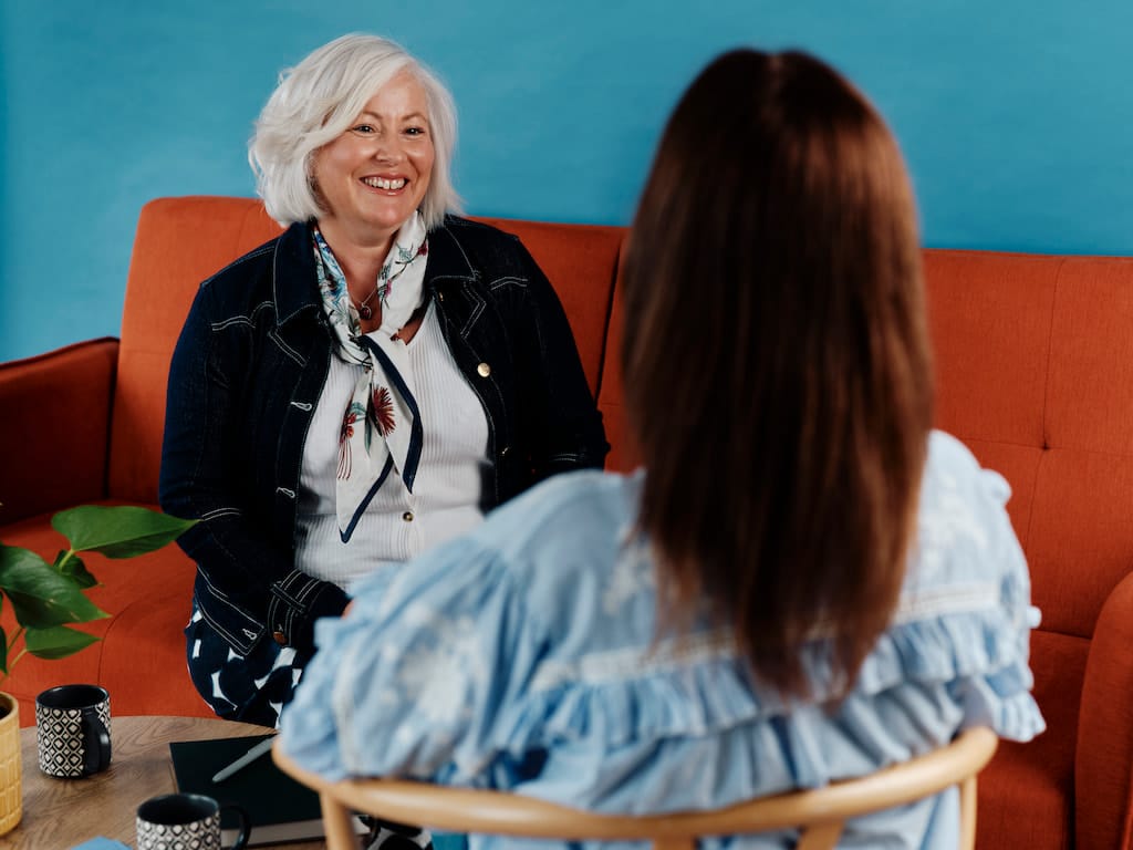 Two women having a conversation on a sofa.