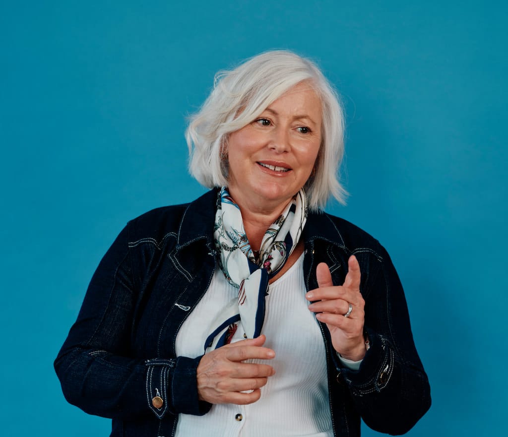 Smiling woman with short white hair and scarf.