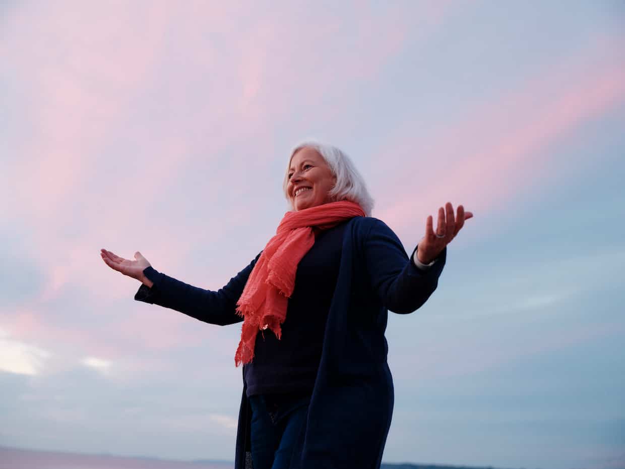 Joyful woman under colourful sunset sky