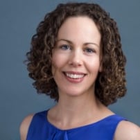 Smiling woman with curly hair and blue dress.