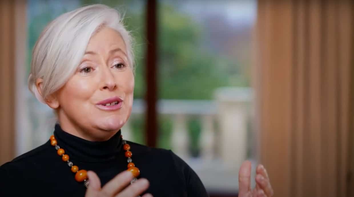 Woman speaking indoors with necklace.